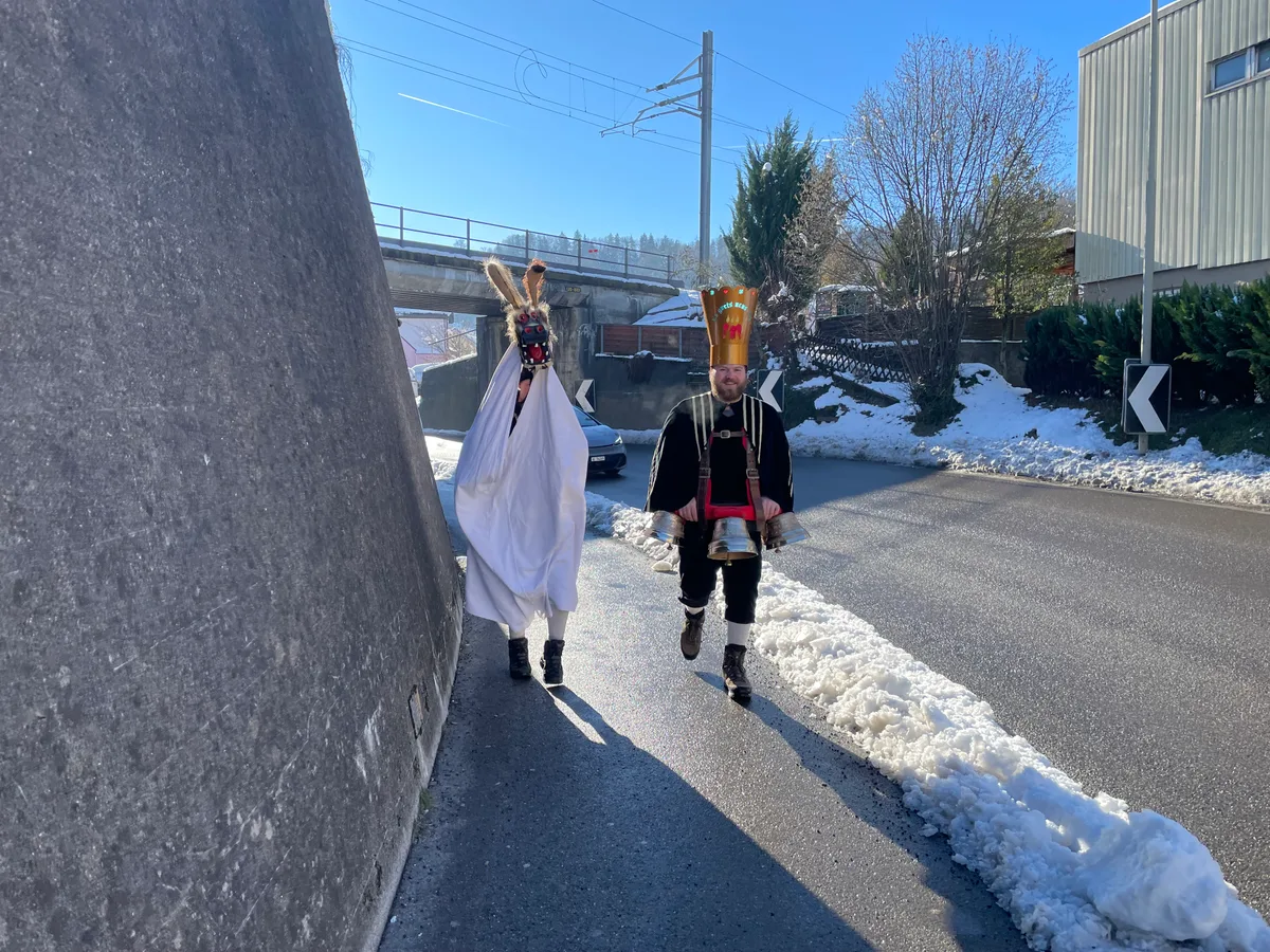 Ein Silvesterchlaus und ein Schnappesel laufen eine Strasse entlang.